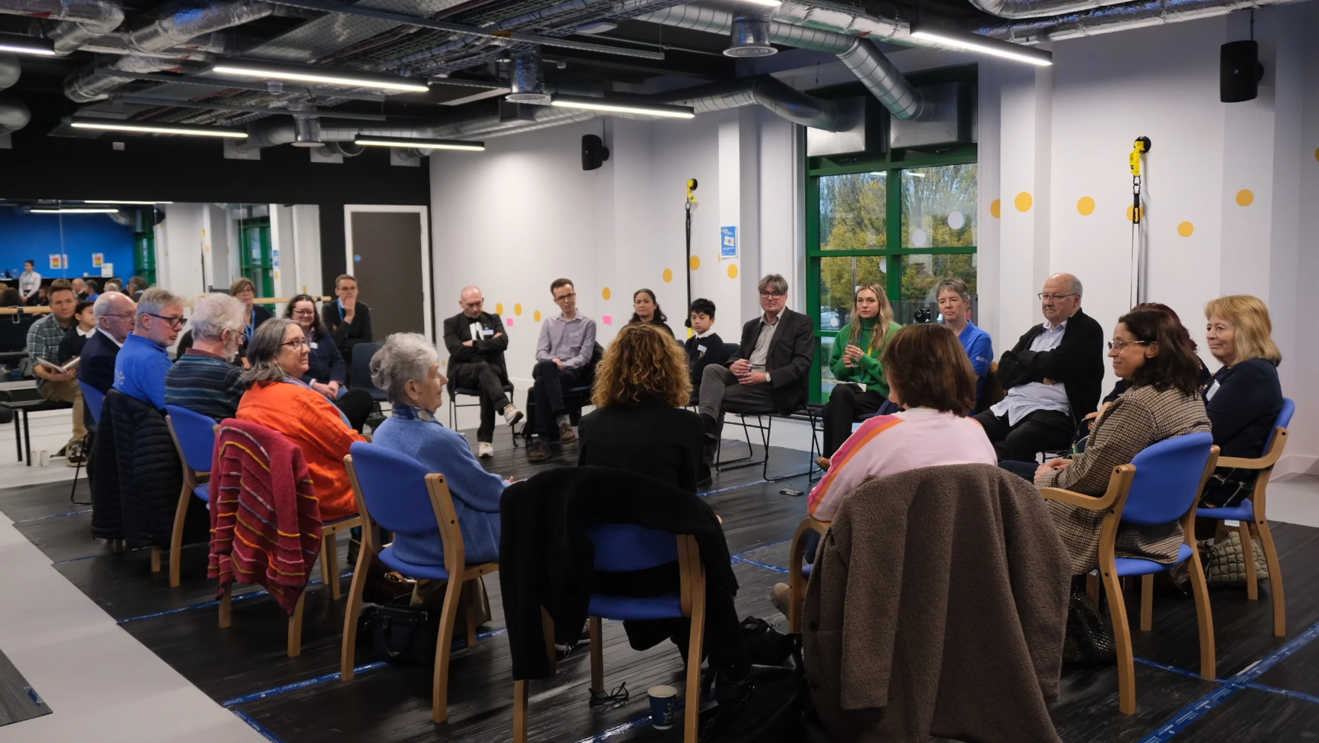 A group of people sit in a large circle in discussion