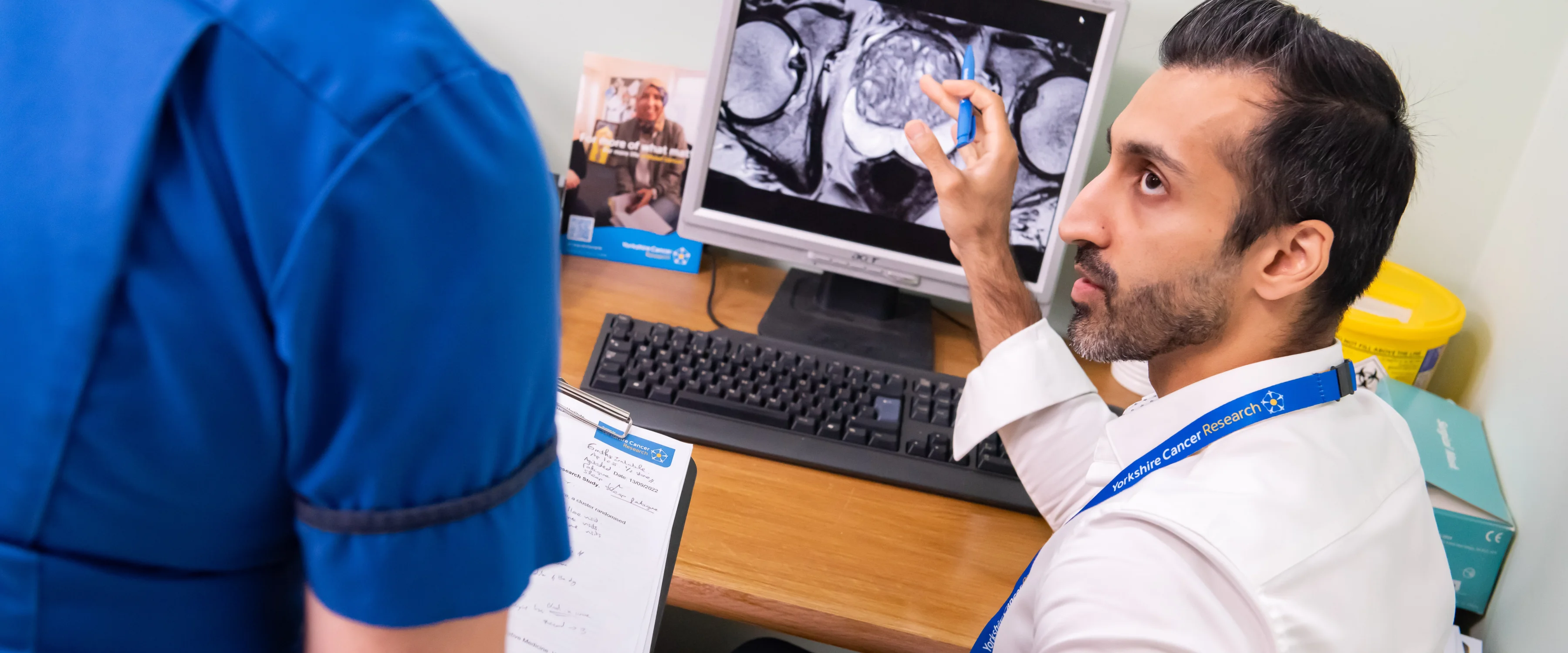 A man sits in front of a screen showing a scan