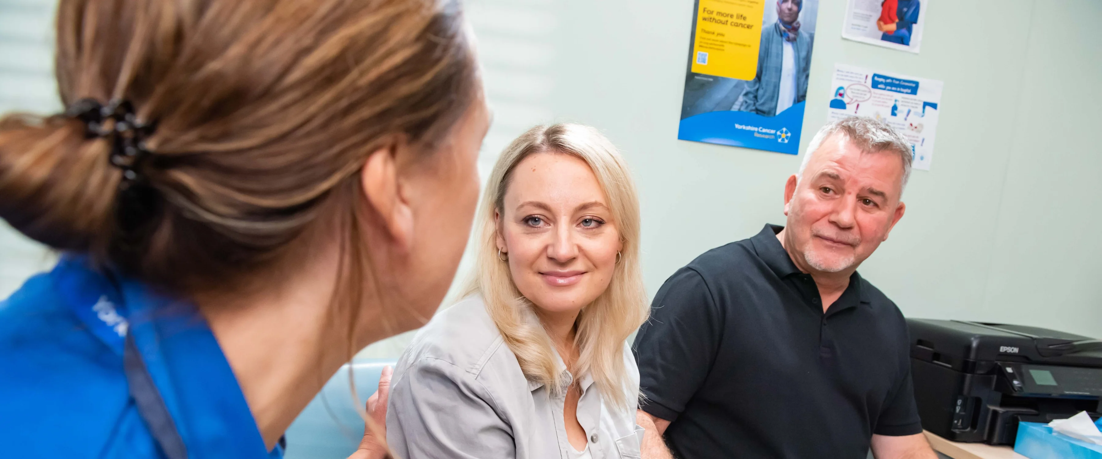 A nurse offering support to a patient and partner in GP practice