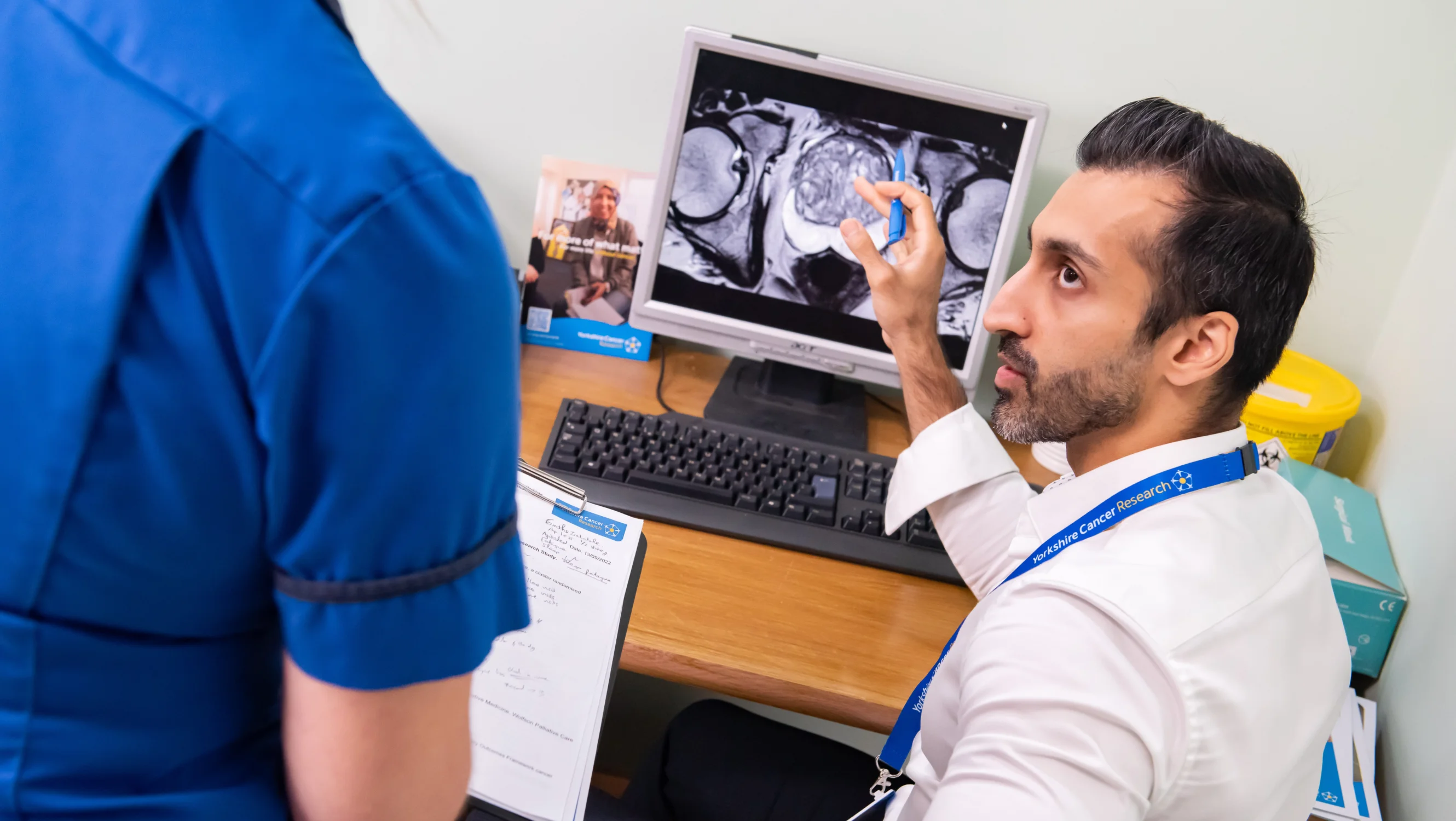 A man sits in front of a screen showing a scan