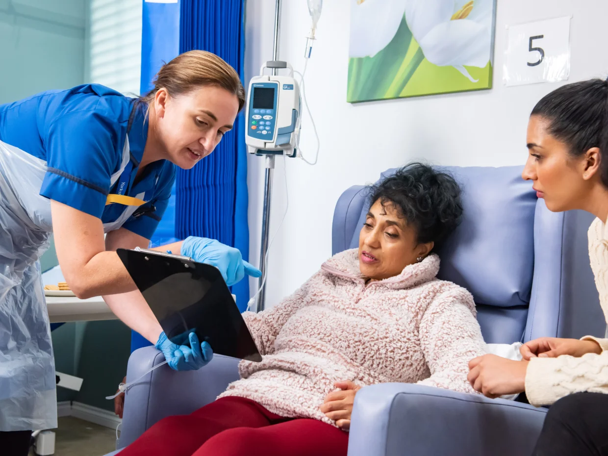 Cancer research nurse talking to cancer patient and her daughter on a hospital ward