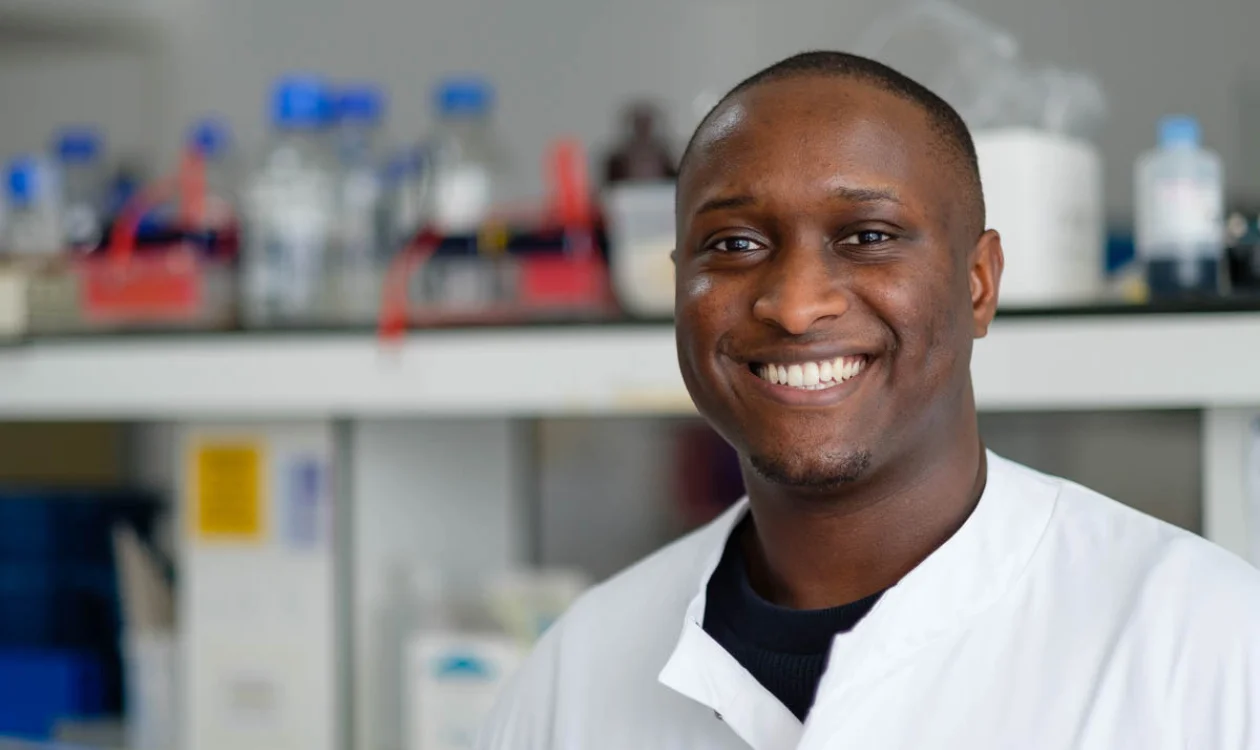 A smiling man in white shirt stands in a lab