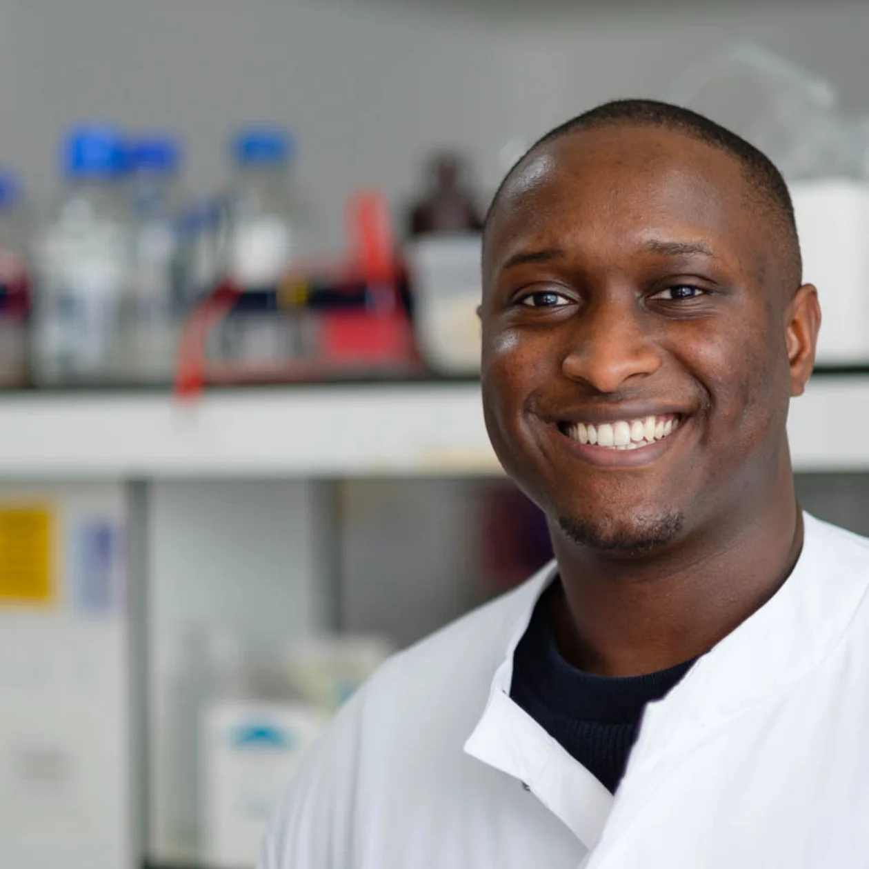 A smiling man in white shirt stands in a lab