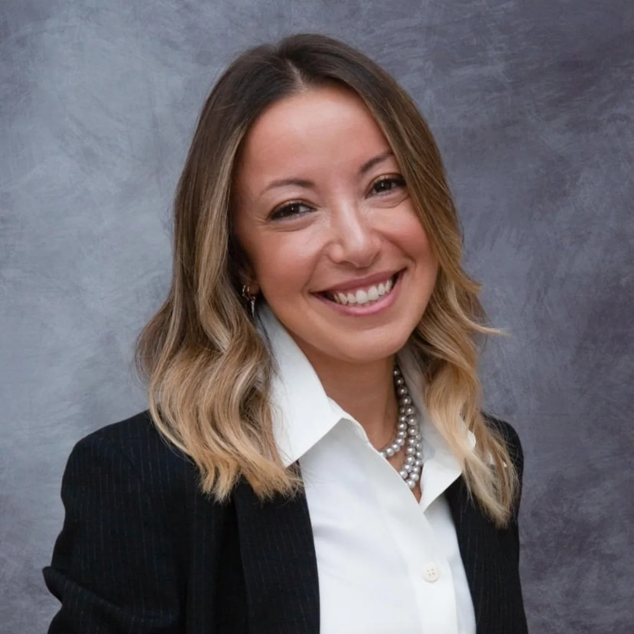 A lady in a shirt and blazer smiling