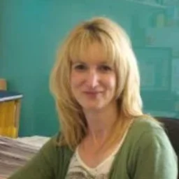 A lady with blonde hair and green top smiling