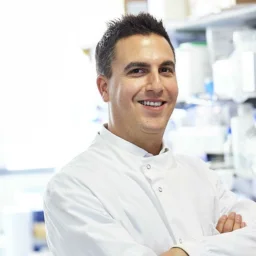 Man standing in a clinical lab with arms folded