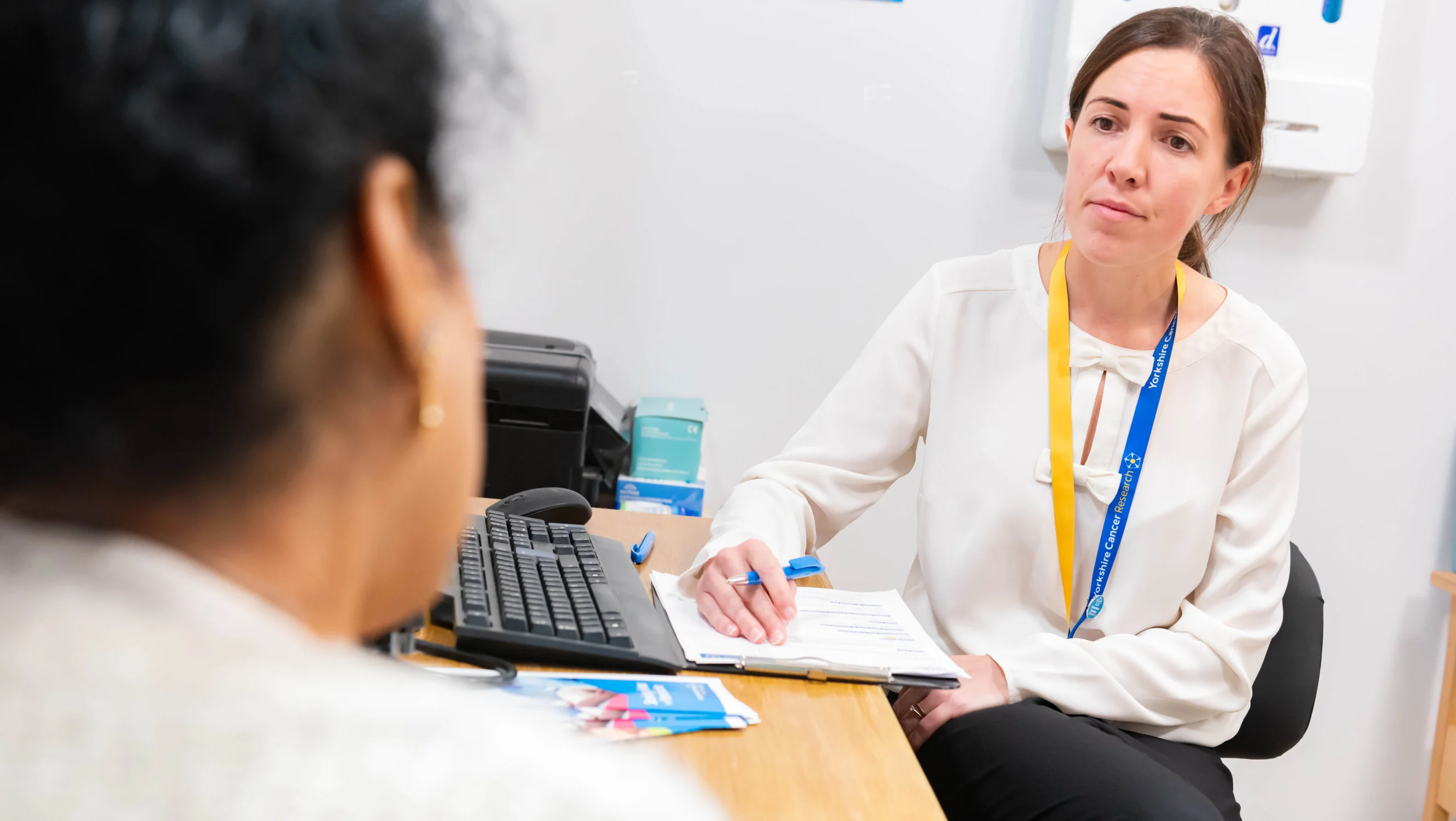 Female doctor sitting at a desk talking to cancer patient