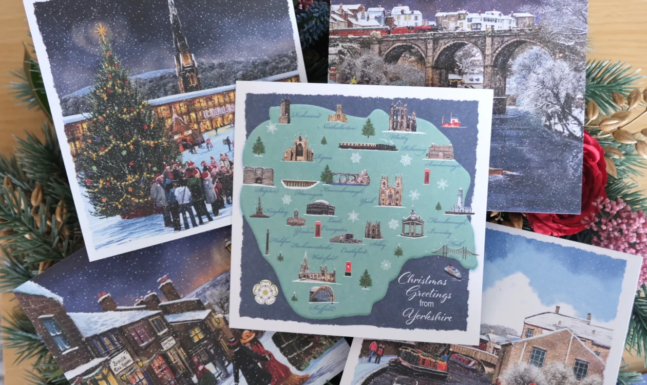 A stack of Christmas cards with different designs lay on a Christmas wreath