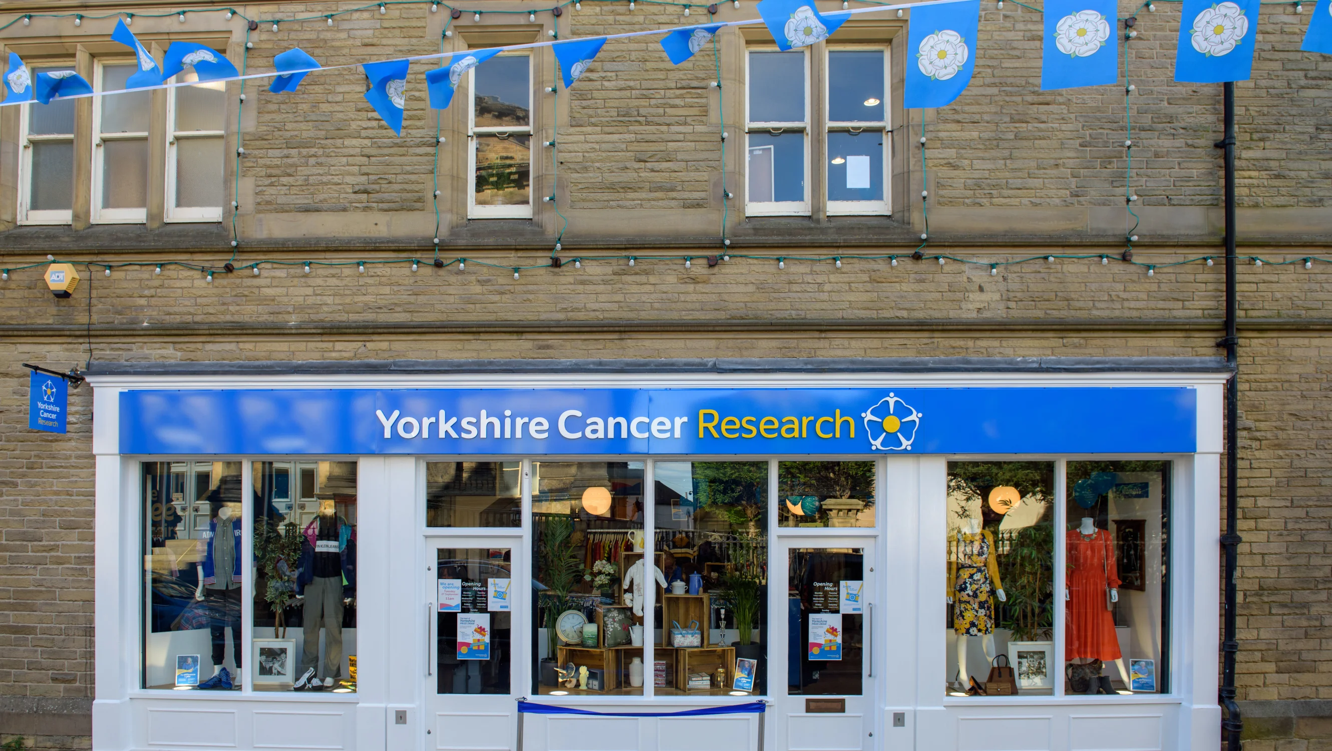 Exterior of a Yorkshire Cancer Research shop with Yorkshire rose bunting outside