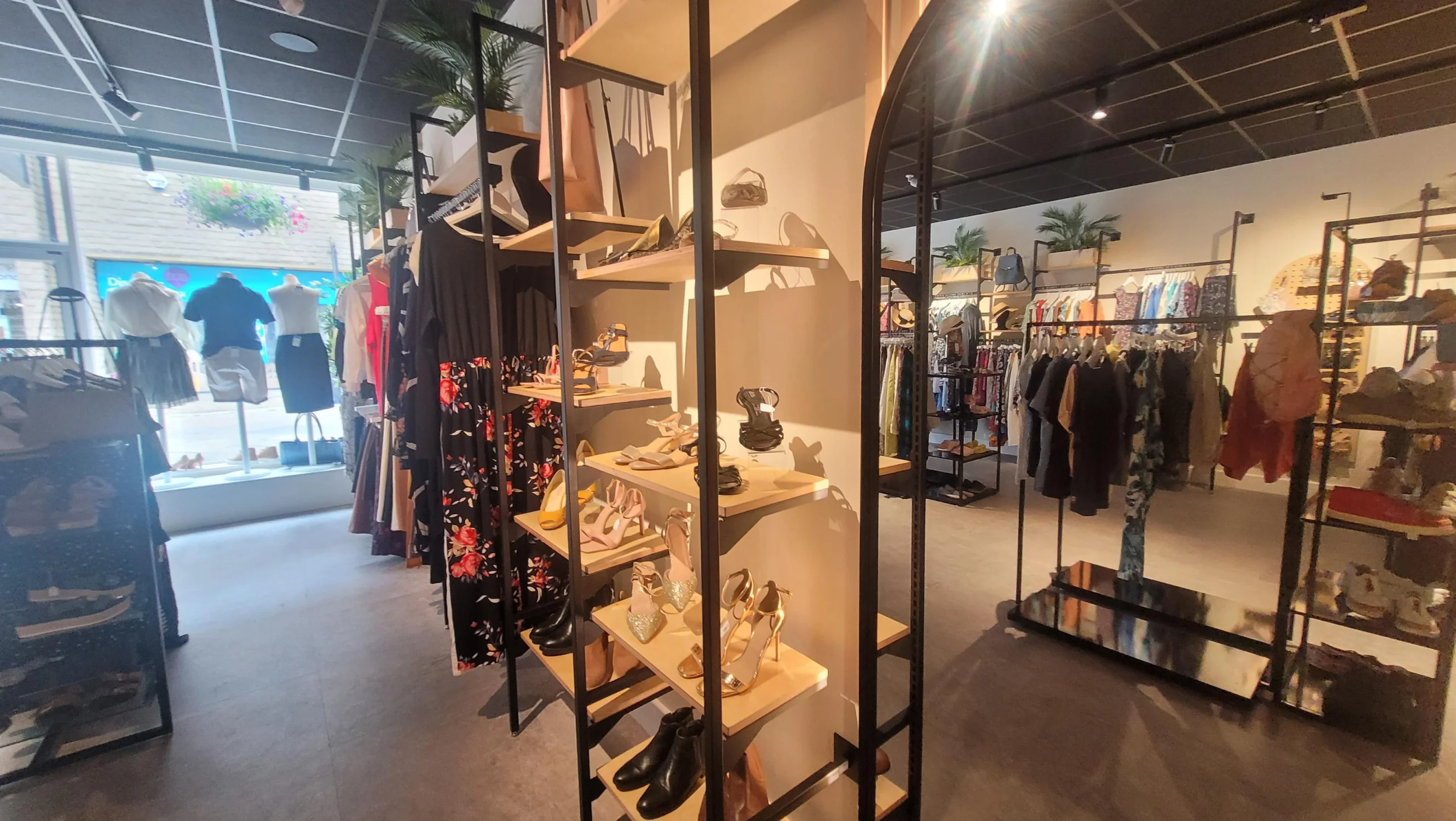 View from the back of a shop to the front window with clothing and shoes in view