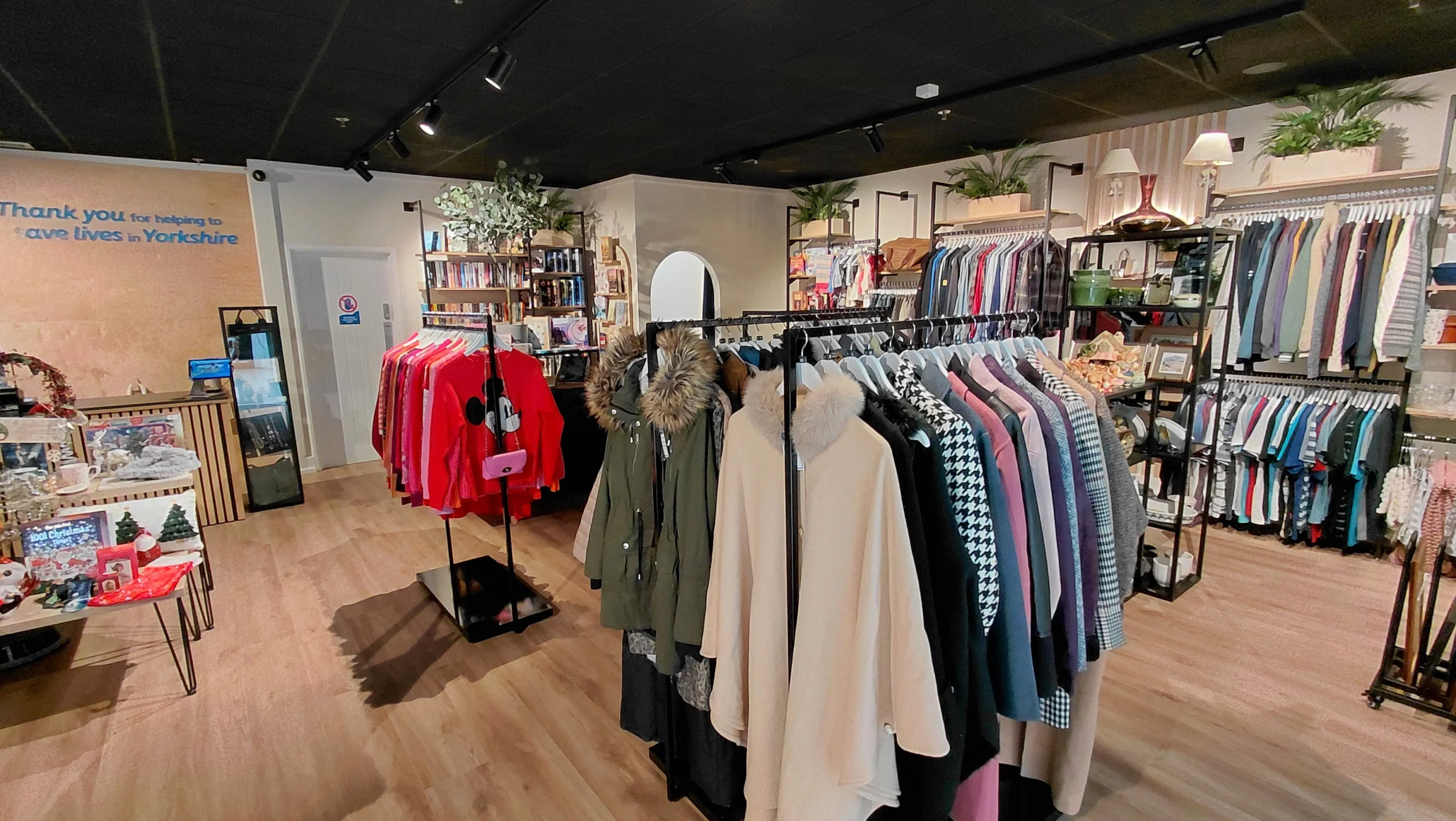Rails of well organised clothing in a modern charity shop