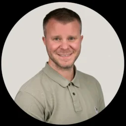 a man with dark hair and stubble in a polo shirt