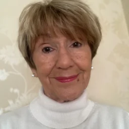 A lady with short hair and a white high neck blouse