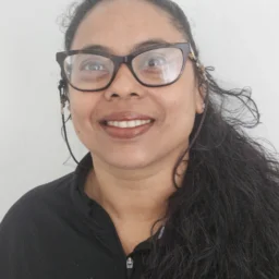 A lady wearing a black shirt and glasses with her hair tied back
