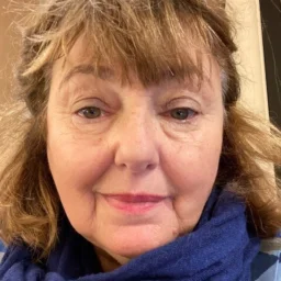 A lady with mid-length brown hair wearing a blue scarf