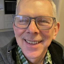 A man with glasses smiles at the camera