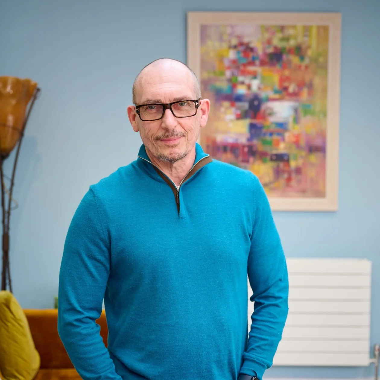 A man with glasses stands in his bright and modern home
