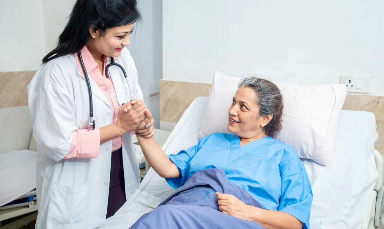 Doctor holding the hand of a patient in bed