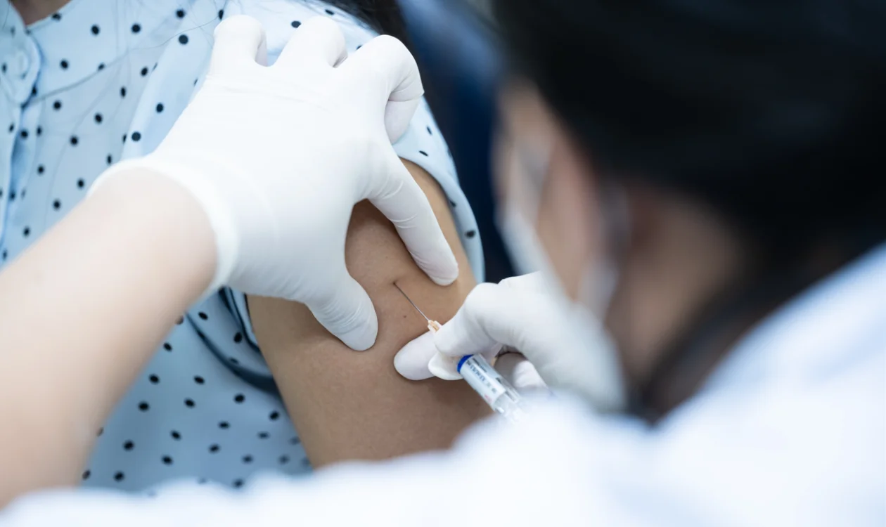 A healthcare professional delivering a vaccine into someone's arm