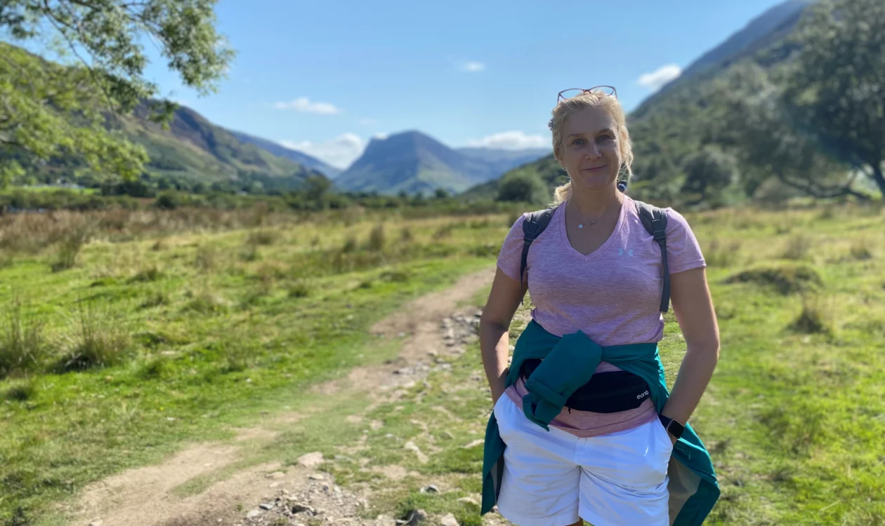 Jayne standing in a field in front of hills