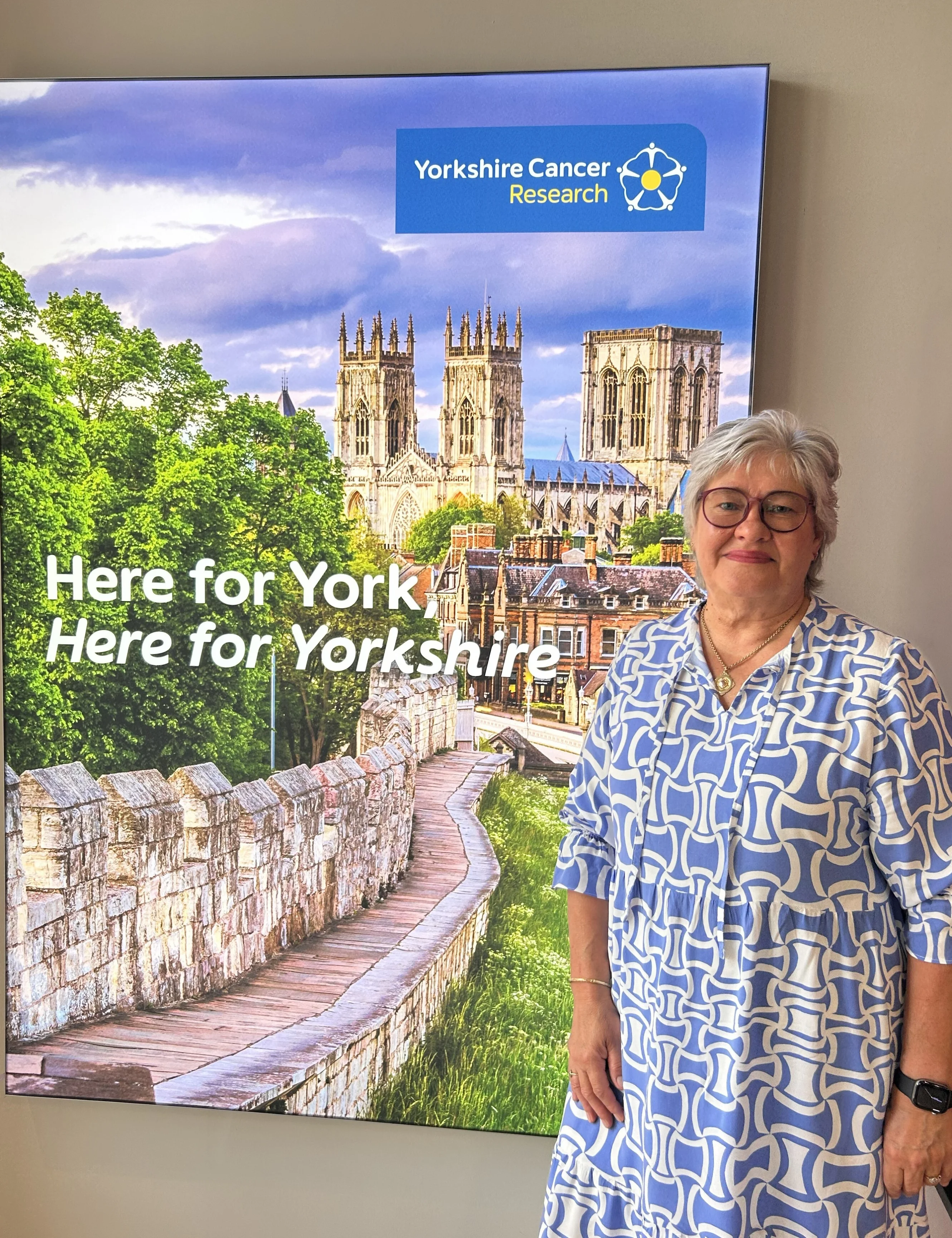 Woman in front of a display with the text "Here for York! Here for Yorkshire"