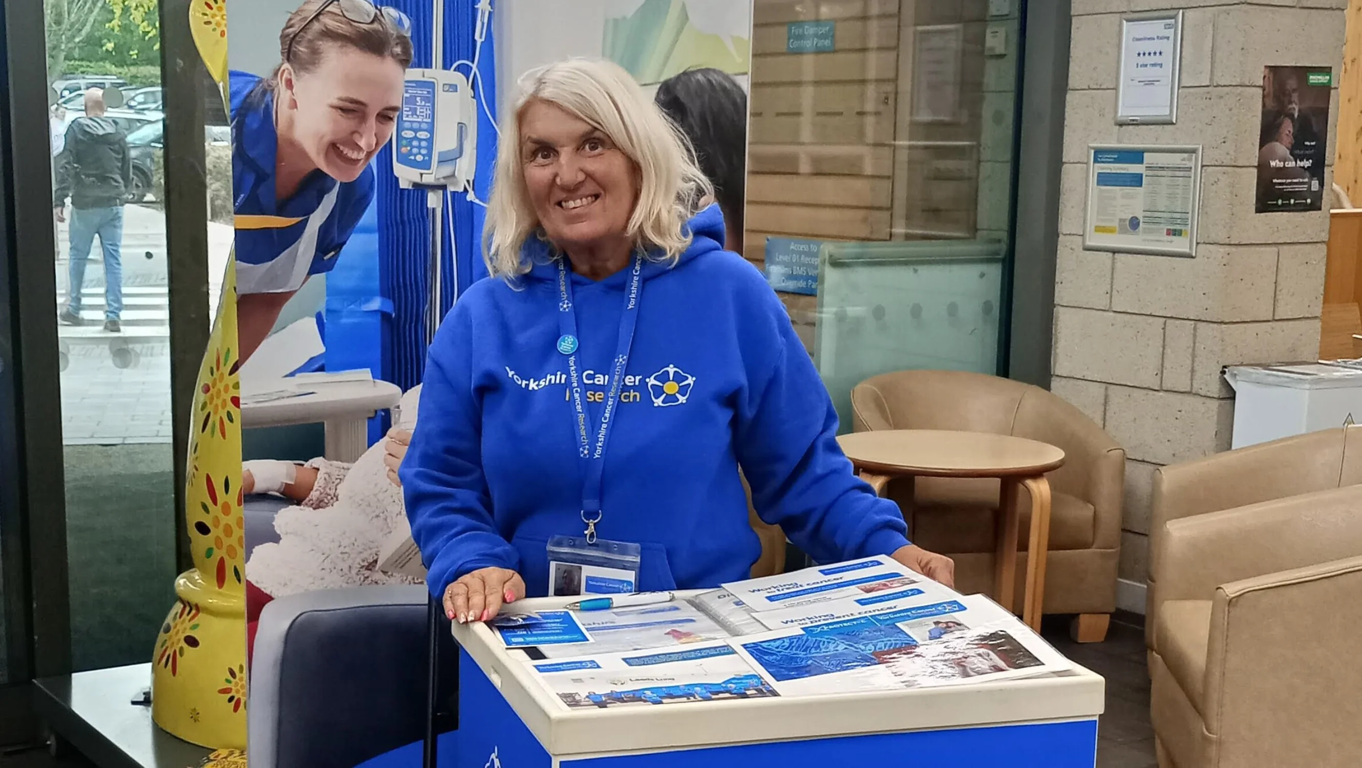 Face to face fundraiser Lorraine standing in front of a Yorkshire Cancer Research Banner and behind a branded podium at Queen's Centre for Oncology and Haematology, Hull.