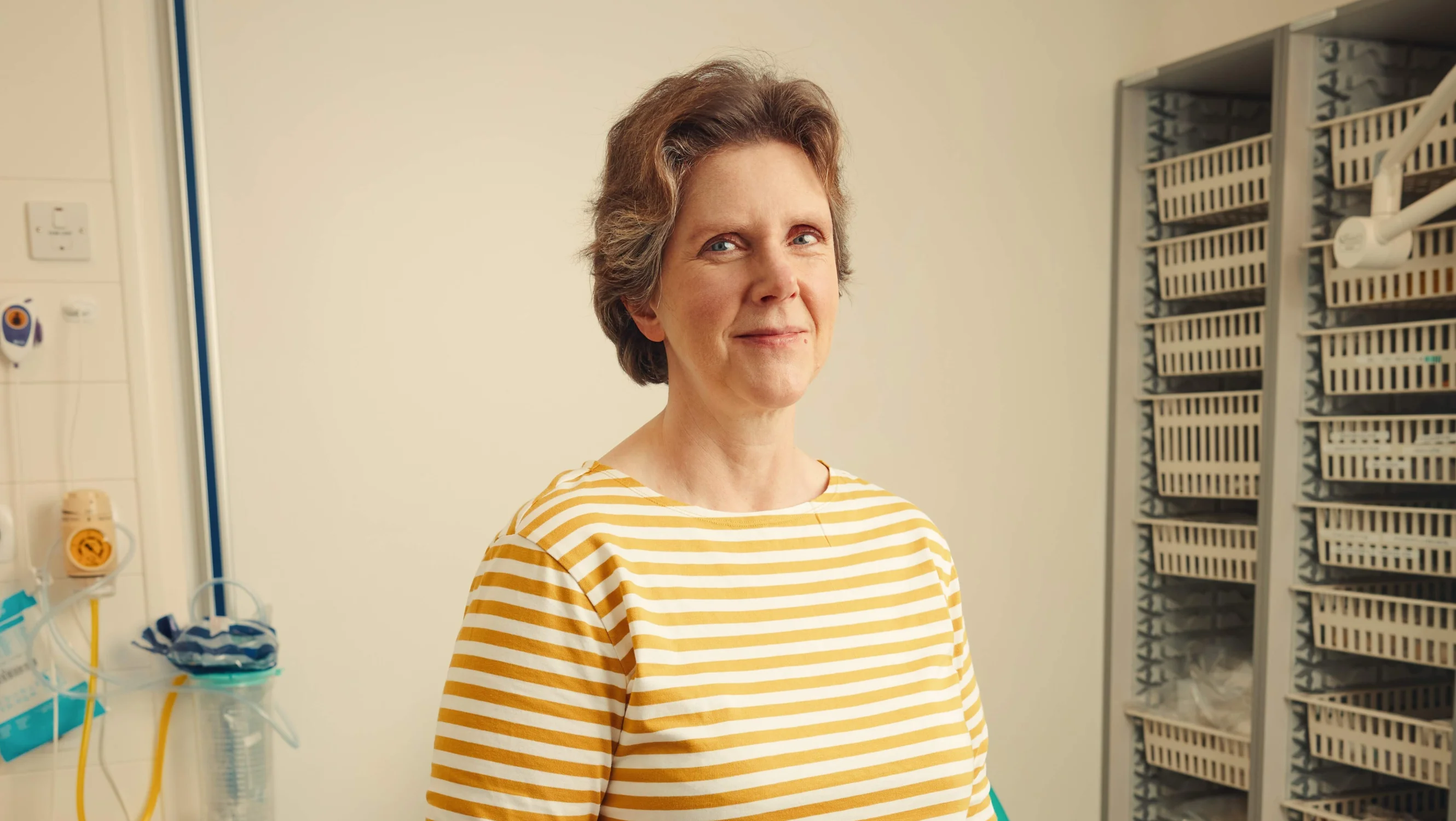 Woman standing in hospital room, looking at camera