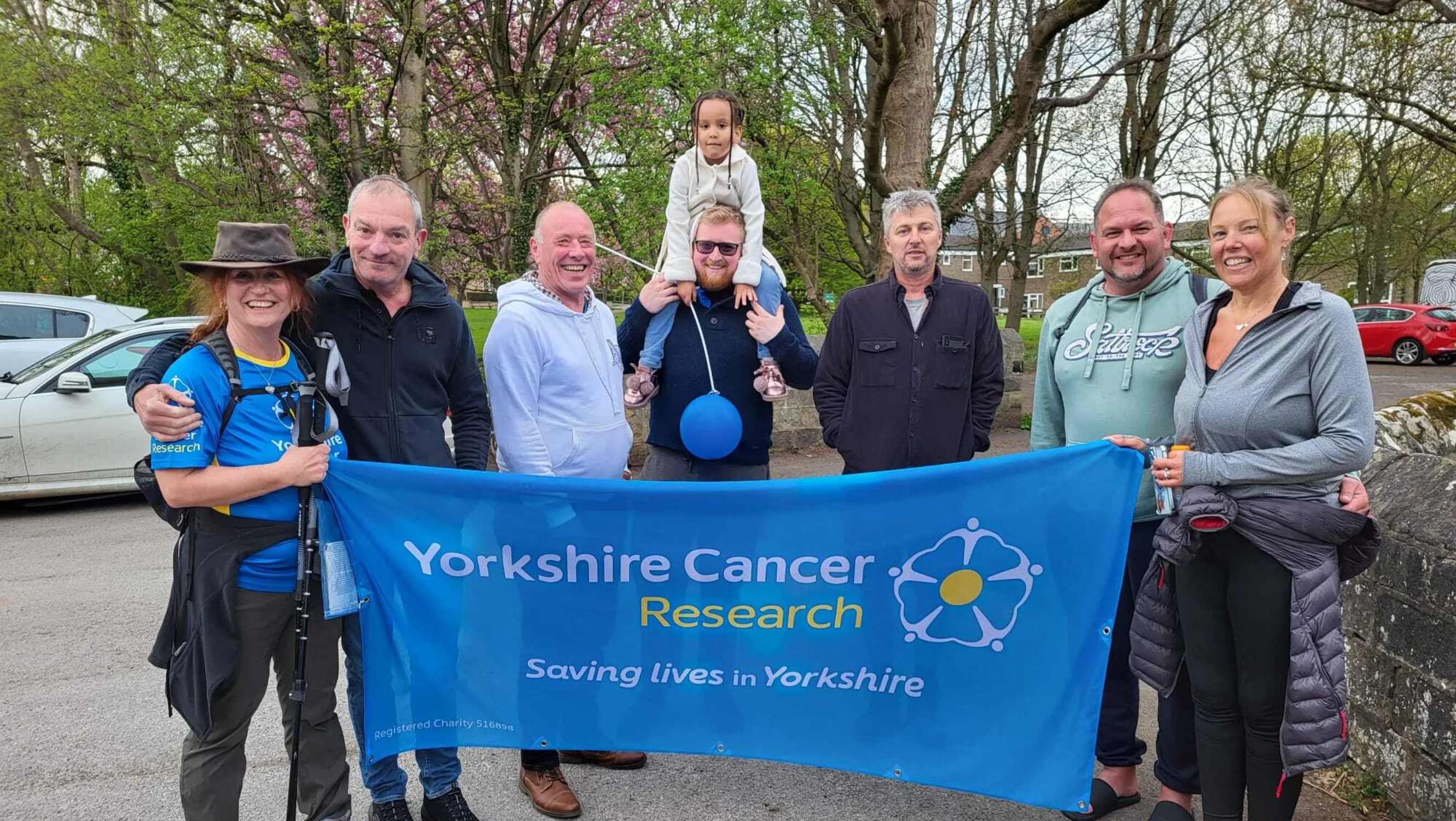 Jackie holding a Yorkshire Cancer Research banner with her friends and family