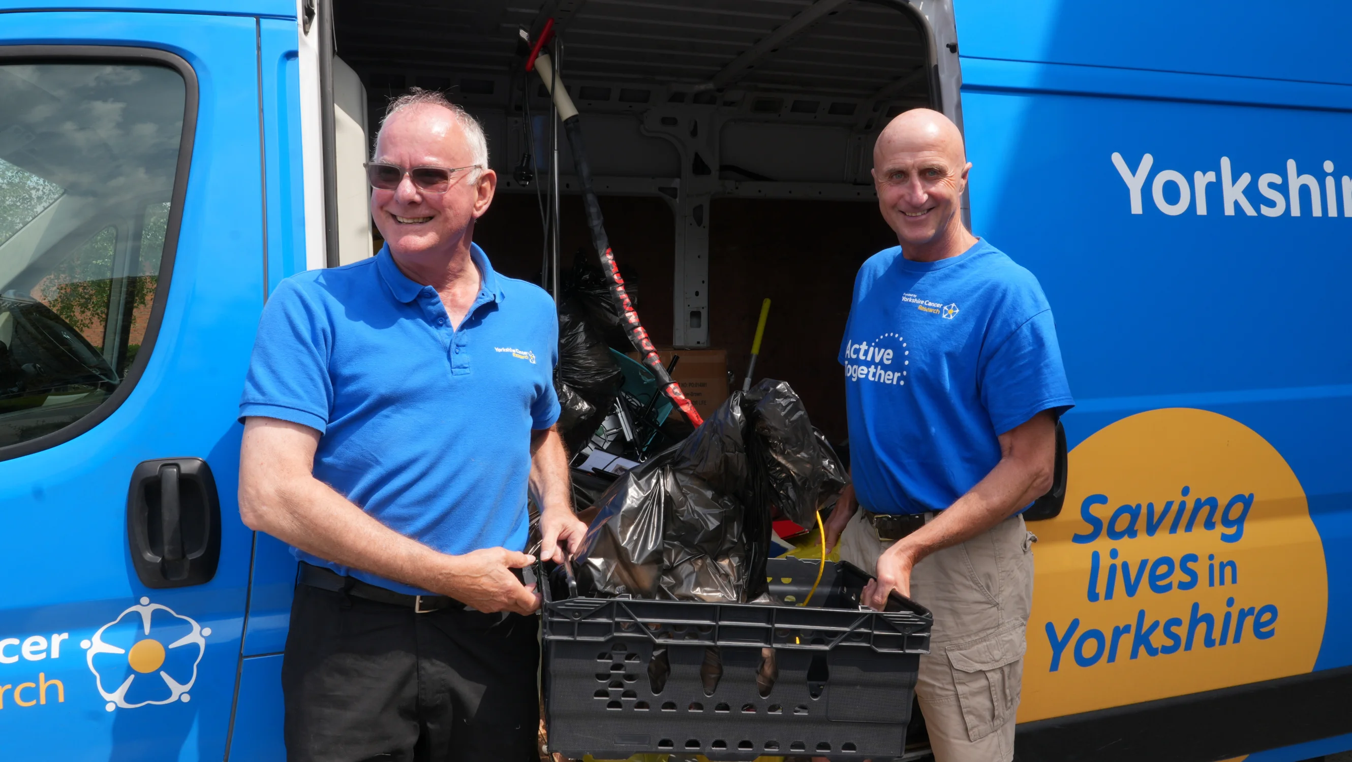 Alastair and Kevin carrying stock out of the Yorkshire Cancer Research van