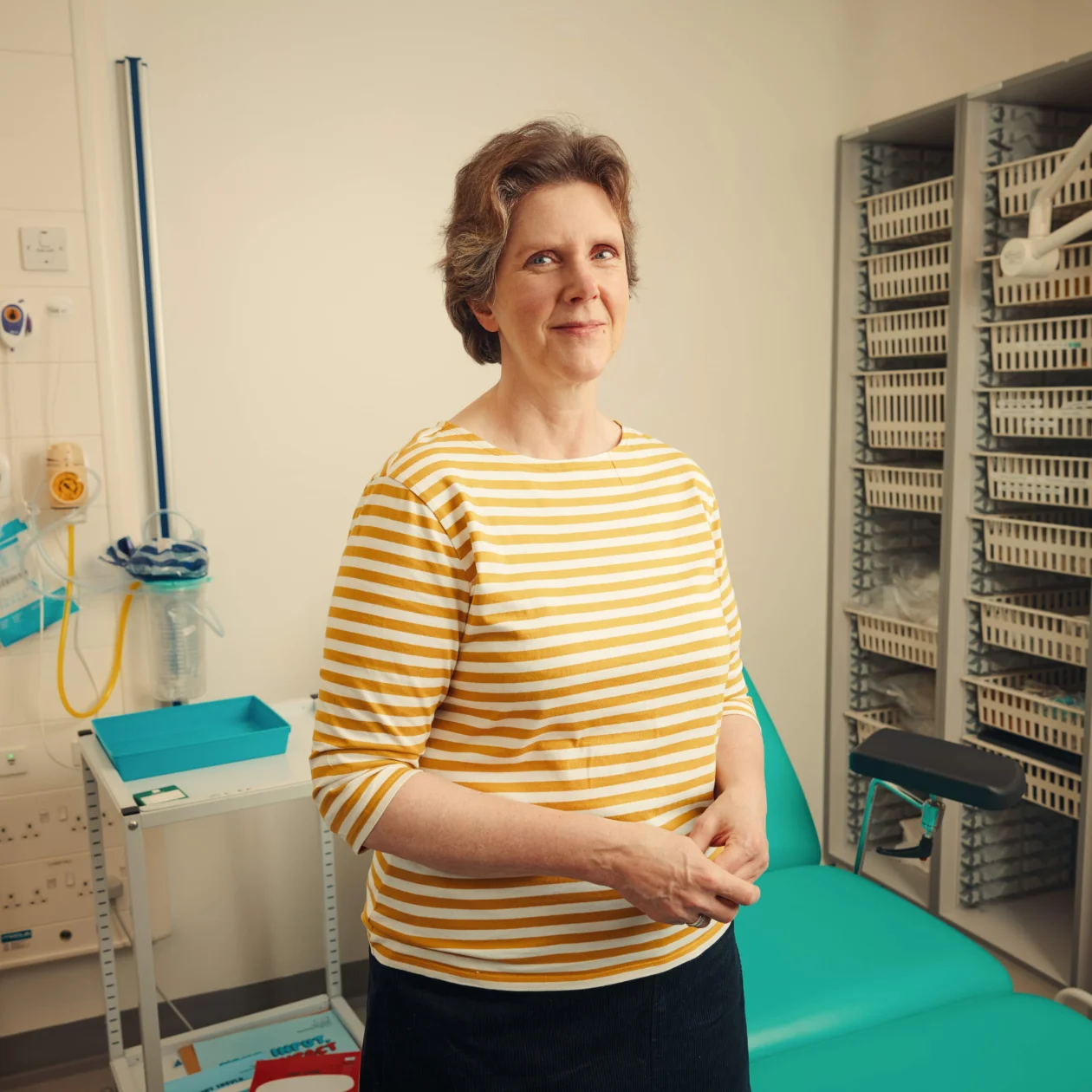 Woman standing in hospital room, looking at camera