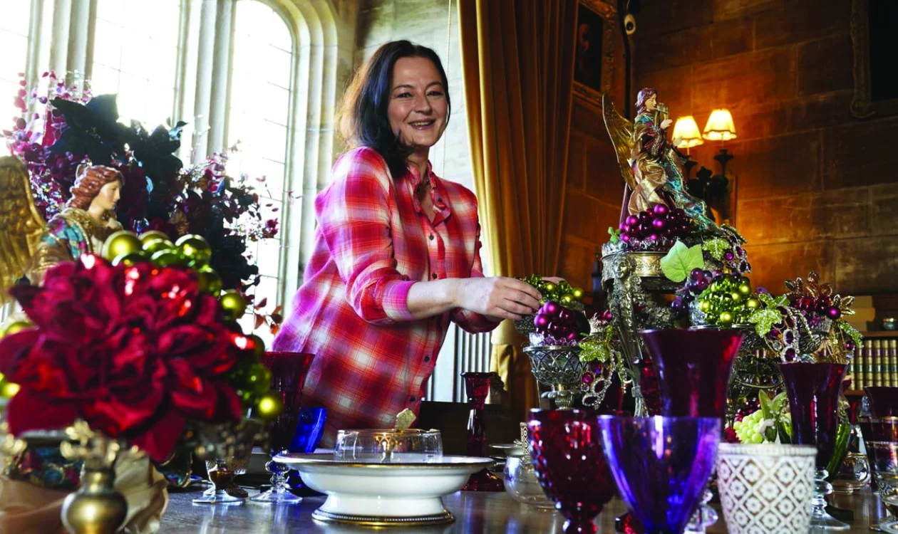 A lady stands in a grand room arranging a display